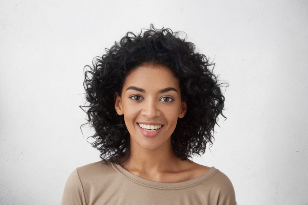 close-up-shot-pretty-woman-with-perfect-teeth-dark-clean-skin-having-rest-indoors-smiling-happily-after-received-good-positive-news